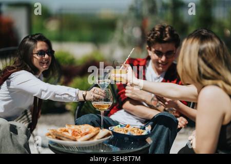Amis adolescents appréciant pizza et boissons à l'extérieur tout en grillant et en riant lors d'un rassemblement décontracté Banque D'Images