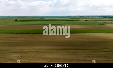Vue aérienne de vastes champs agricoles et de terres cultivées sous un ciel nuageux près de Novi Sad, Voïvodine, Serbie. Banque D'Images