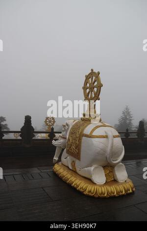 Vue latérale d'une statue sacrée d'éléphant à six défenses agenouillée dans un matin brumeux au sommet doré du mont Emei, province chinoise du Sichuan Banque D'Images