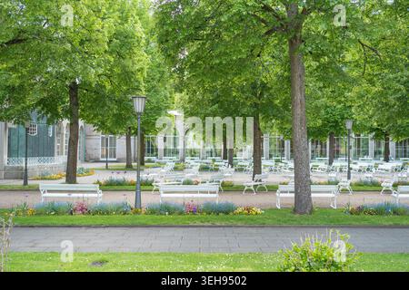 Aire de promenade dans un jardin public avec pelouse verte, lanterne vintage et rangées de sièges. Concept d'aménagement paysager et d'environnement. Banque D'Images