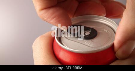 Ouverture d'une canette de cola ou de soda. Gros plan de la canette de boisson en aluminium ouverte à la main avec languette de retrait. Rafraîchissant contenant de boisson gazeuse au cola ou au soda avec méta Banque D'Images
