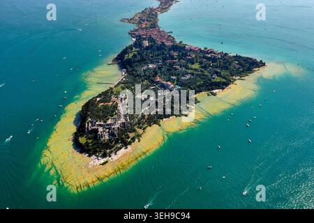 Vue aérienne de la péninsule de Sirmione sur le lac de Garde avec les ruines de Grotte di Catullo entourées d'eau turquoise et de verdure luxuriante en Italie. Banque D'Images