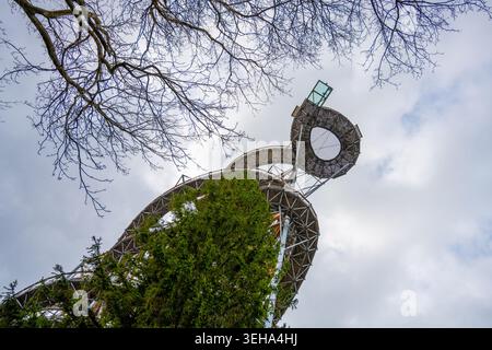 Une grande tour métallique se dresse entourée d'arbres. La vue est du niveau du sol en regardant vers le haut vers la structure. De légers nuages remplissent le ciel au-dessus du towe Banque D'Images