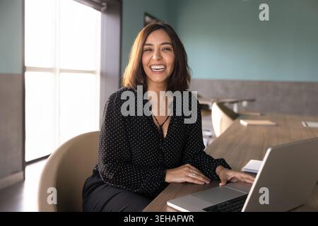 Portrait de femme d'affaires riante travaillant sur ordinateur portable dans le bureau Banque D'Images