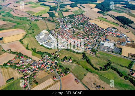 Vue aérienne de la ville de Wachenroth avec des maisons au toit rouge nichées au milieu de vastes champs agricoles et de prairies verdoyantes sous un ciel clair à Wachen Banque D'Images