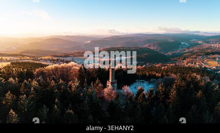 La tour de guet Stepanka se dresse dans les montagnes de Jizera pendant l'hiver. Le soleil se couche derrière des collines lointaines, projetant la lumière sur les arbres givrés et les s. Banque D'Images