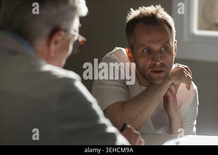 Homme adulte discutant des préoccupations de santé mentale pendant la séance de thérapie Banque D'Images