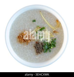 Vue de dessus de la bouillie de riz ou de la soupe de riz ou du riz bouilli avec des épices et de la viande de poulet dans un bol blanc est isolé sur fond blanc avec chemin de découpage. Banque D'Images