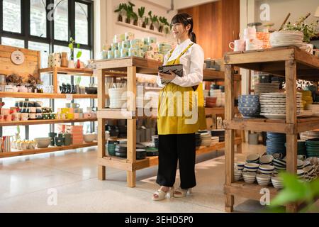 Personnel de magasin debout et vérifiant les produits à l'intérieur du magasin, tenant des articles pendant la préparation de l'affichage ou du service à la clientèle Banque D'Images