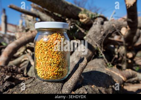 Granules de pollen d'abeille naturel stockées dans un bocal en verre, mettant en valeur un complément alimentaire naturel sain et un produit apicole d'apparence rustique. Banque D'Images