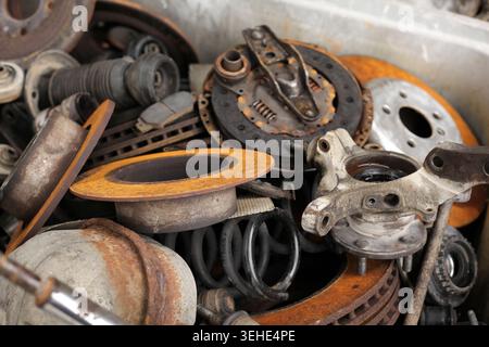 Pile de diverses pièces automobiles usagées et rouillées collectées dans un bac de recyclage de métal à un chantier naval. Banque D'Images