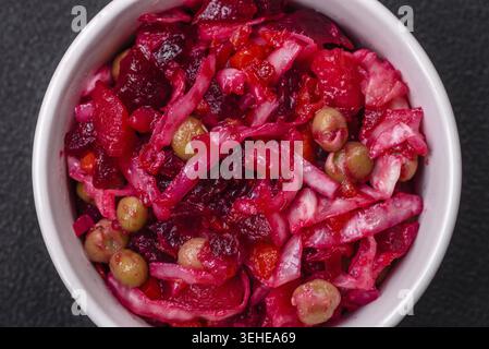 Nourriture, délicieuse salade de vinigret juteuse de légumes bouillis, pommes de terre, betteraves, pot, chou et carottes avec sel et épices sur un fond de béton foncé Banque D'Images