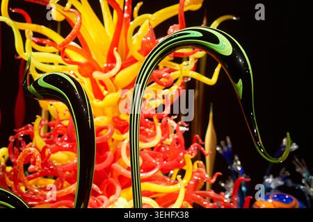 Vue rapprochée vibrante de sculptures en verre soufflé à la main élaborées présentant des formes courbes organiques en jaune vif, rouge et noir avec des rayures vertes Banque D'Images