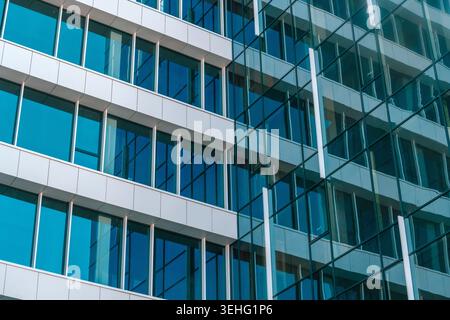 Façade moderne de bâtiment de bureaux en verre avec fenêtres bleues réfléchissantes et lignes géométriques, transmettant l'entreprise, l'architecture urbaine, le professionnalisme, et co Banque D'Images