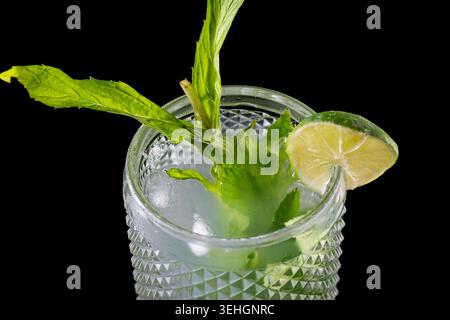 Cocktail de mojito frais avec des feuilles de menthe citron vert et de la glace sur fond noir Banque D'Images