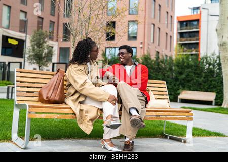 Positif couple afro-américain homme et femme assis dans la ville appréciant les communications relationnelles. Banque D'Images