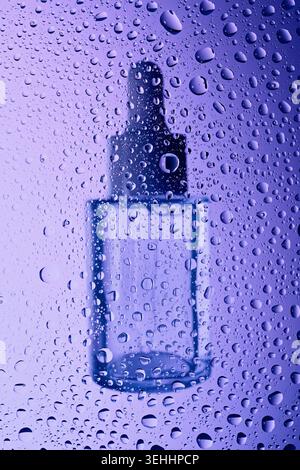 Flacon compte-gouttes transparent apparaissant à travers la surface en verre humide avec condensation Banque D'Images