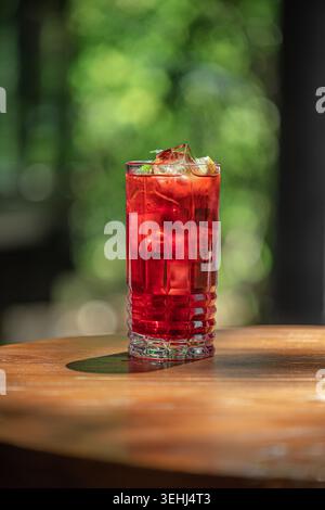 Cocktail rouge avec de la glace sur la table en bois Banque D'Images
