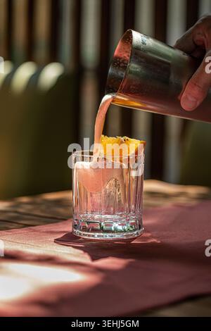 Verser le cocktail frais dans le verre de whisky Banque D'Images