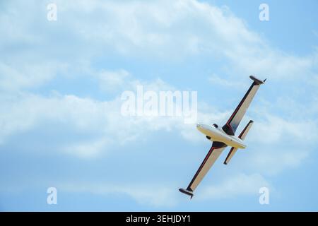 Vue d'un petit avion à réaction effectuant une manœuvre acrobatique contre un ciel bleu avec de légers nuages à Veliki Radinci, Voïvodine, Serbie. Banque D'Images