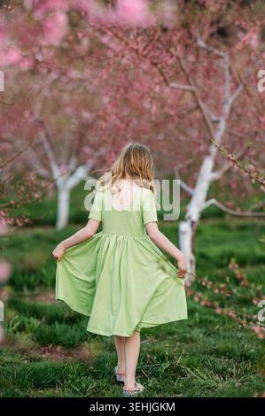 Fille tenant la robe dans le verger de fleurs roses Banque D'Images