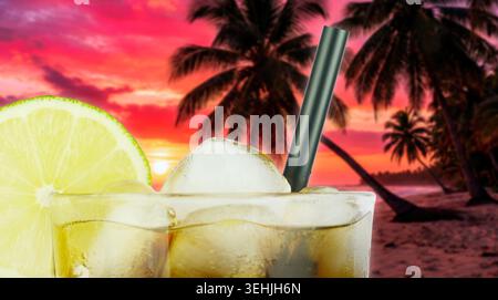 Un cocktail rafraîchissant avec des glaçons et une tranche de citron vert, sur fond de plage tropicale au coucher du soleil Banque D'Images