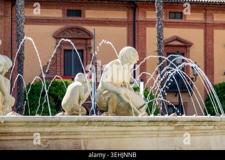 Sevilla, Sevilla - Espagne ? 04-19-2024 : fontaine en pierre AA avec sculptures d'enfants, jets d'eau en forme d'arc, éclairés par la lumière du soleil. Banque D'Images