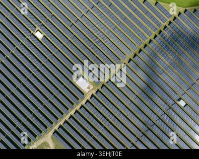 Vue aérienne d'une grande ferme solaire avec des rangées de panneaux photovoltaïques bleus et d'herbe verte Allemagne. Banque D'Images