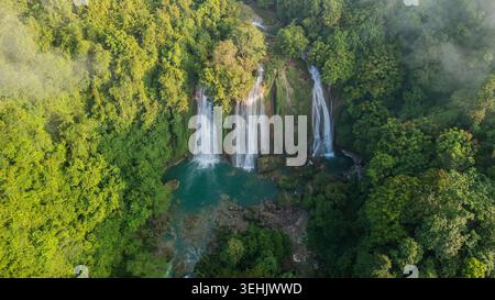 Vue aérienne de la cascade de Cikaso avec ses trois cascades distinctes tombant dans une piscine turquoise entourée d'une forêt tropicale luxuriante et de brume matinale Banque D'Images