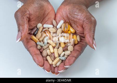 Deux mains humaines tiennent une variété de capsules pharmaceutiques et de comprimés de différentes couleurs, formes et tailles. Produits pharmaceutiques. BSIP 016938 069 Banque D'Images