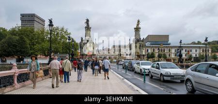 Piétons et circulation automobile traversant le pont historique Maria Cristina avec ses obélisques monumentaux à Saint-Sébastien, Espagne, Europe Banque D'Images