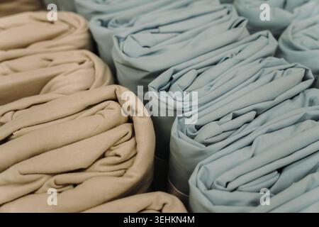 Tissu textile roulé dans des tons beige et bleu disposés en rangées. Matériau doux et concept d'aménagement moderne pour des projets d'intérieur domestique. Banque D'Images