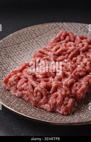Nourriture, farce ou boeuf cru haché ou porc avec sel et épices sur fond noir Banque D'Images
