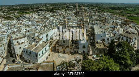 Vue aérienne de la ville touristique de Locorotondo avec ses maisons typiques blanchies à la chaux, l'église de San Giorgio Martire et la vallée d'Itria. Banque D'Images