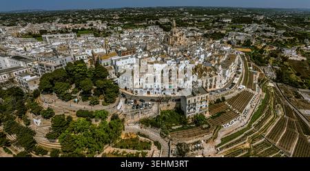 Vue aérienne de la ville touristique de Locorotondo avec ses maisons typiques blanchies à la chaux, l'église de San Giorgio Martire et la vallée d'Itria. Banque D'Images