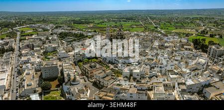 Vue aérienne de la ville touristique de Locorotondo avec ses maisons typiques blanchies à la chaux, l'église de San Giorgio Martire et la vallée d'Itria. Banque D'Images