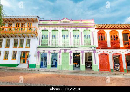Des bâtiments coloniaux dynamiques avec des balcons en bois et des façades pastel bordent une rue calme à Jerico, Antioquia, une ville traditionnelle colombienne sous un Clo Banque D'Images