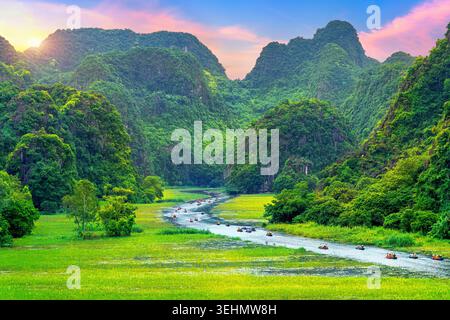 Les touristes flottent en bateau sur la rivière du parc national de Tam Coc, au Vietnam. Banque D'Images