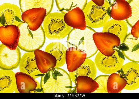 Vue de dessus vibrante de kiwi tranchés, de citron et de fraises fraîches disposés sur un fond blanc propre, créant un motif de fruits d'été lumineux pour la nourriture d Banque D'Images