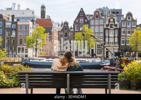 Une mère et sa fille s'assoient près d'un banc à Amsterdam, profitant de leurs vacances de printemps tout en explorant la ville et les canaux. Banque D'Images