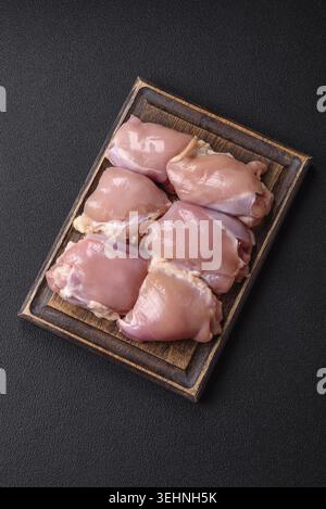 Nourriture, filets de cuisse de poulet crus frais avec du sel, des épices et des herbes sur un fond de béton foncé Banque D'Images