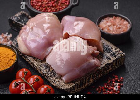 Nourriture, filets de cuisse de poulet crus frais avec du sel, des épices et des herbes sur un fond de béton foncé Banque D'Images