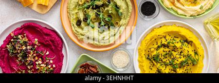 Une planche de charcuterie vibrante présente du brocoli, du curcuma, du houmous classique et de la betterave, associés à des olives, craquelins, et garnitures fraîches, parfait pour Banque D'Images