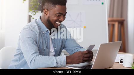 Happy black manager looking at smartphone la lecture à l'écran message agréable Banque D'Images