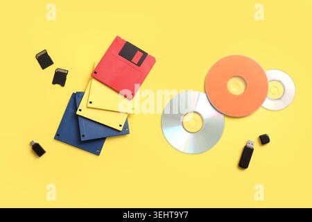 CD, disquettes, cartes SD et lecteur flash USB sur fond jaune Banque D'Images