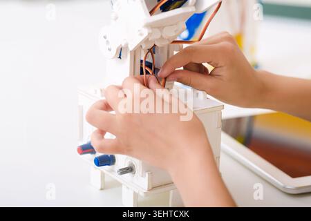 Mains assemblage d'un modèle de robot avec des fils et des composants dans un cadre d'atelier lumineux Banque D'Images