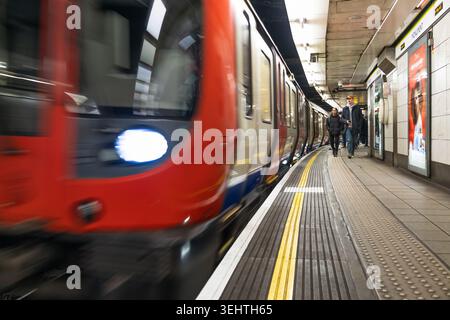 Train de métro londonien qui passe devant un quai de gare. Londres, Royaume-Uni, 10 décembre 2023 Banque D'Images
