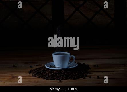 Moody Still Life de café chaud fraîchement préparé dans une tasse en céramique blanche avec vapeur visible. Banque D'Images