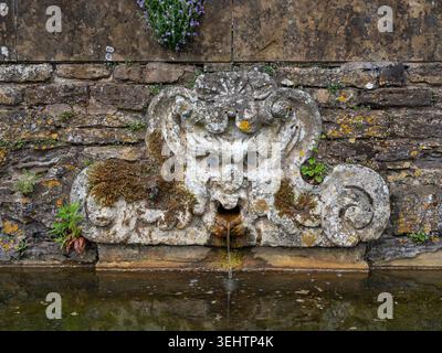 Une vieille eau altérée jaillit dans les jardins d'Ashby Manor, une grande maison de campagne, Ashby St Ledgers, Northamptonshire, Royaume-Uni Banque D'Images