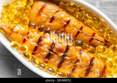 Filets de maquereau fumé avec capsules d'huile de foie de morue dans un plat blanc. Concept sain de régime Oméga 3 Banque D'Images